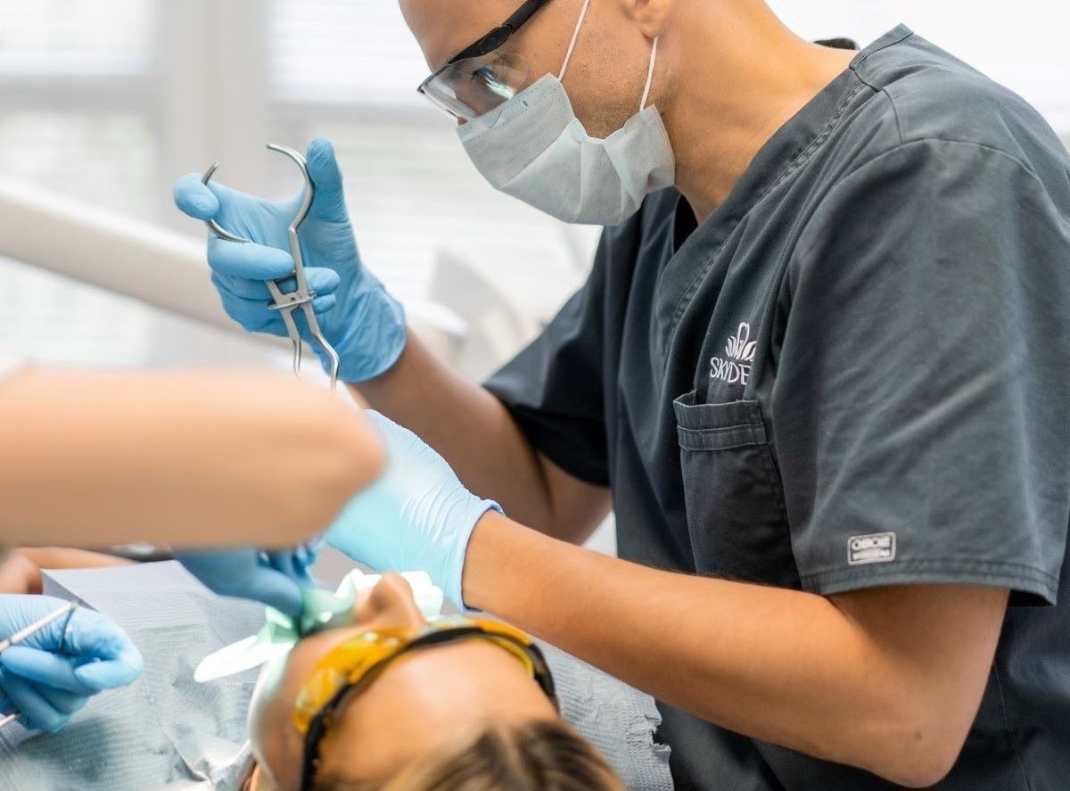 Oral surgery in Hamilton, Charlton Dentistry surgical dentist performing a precise tooth extraction procedure on a patient under local anesthesia using sterile forceps.