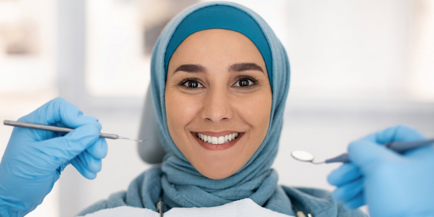 Smile makeover Hamilton, smiling patient in a teal hijab during a cosmetic dentistry exam at Charlton Dentistry.